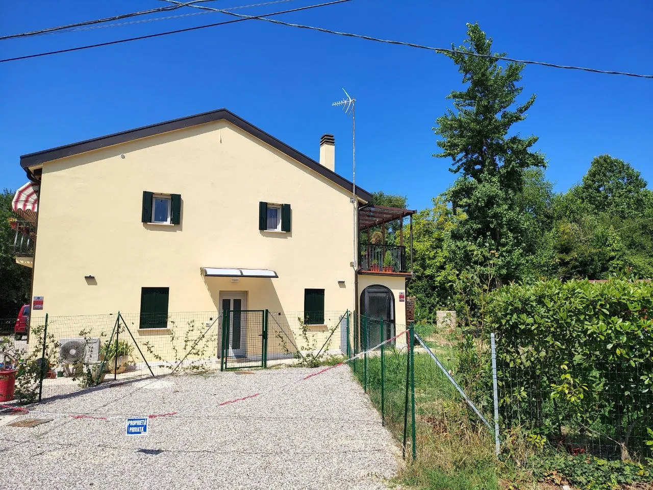 La casa vista dal cortile, con il prato e la siepe